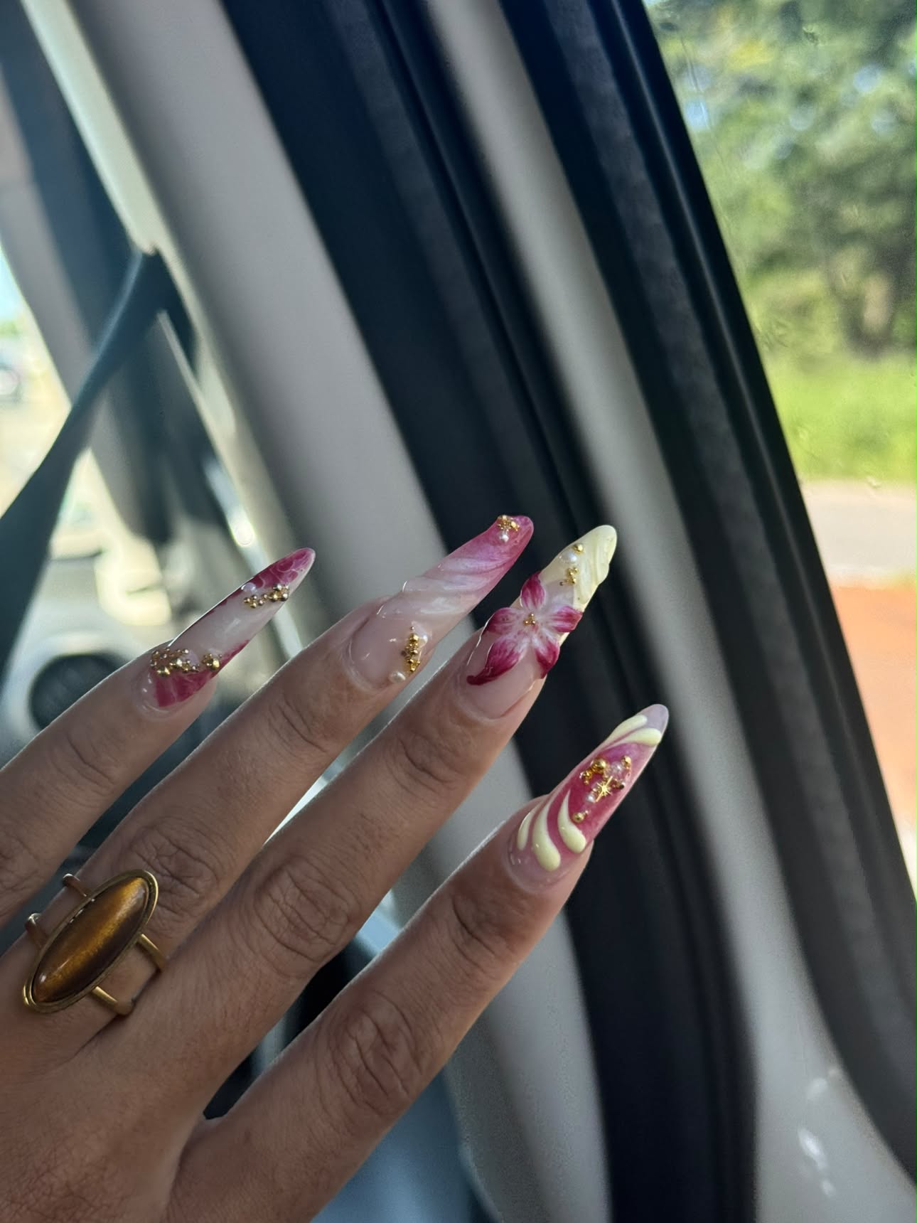 Longs ongles stiletto décorés de fleurs roses, de perles et de micro-billes dorées