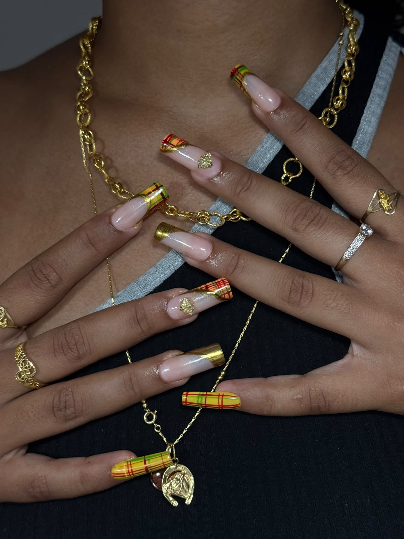 Ongles à bouts madras jaune, rouge et vert, mêlés à des finitions or et des bijoux dorés