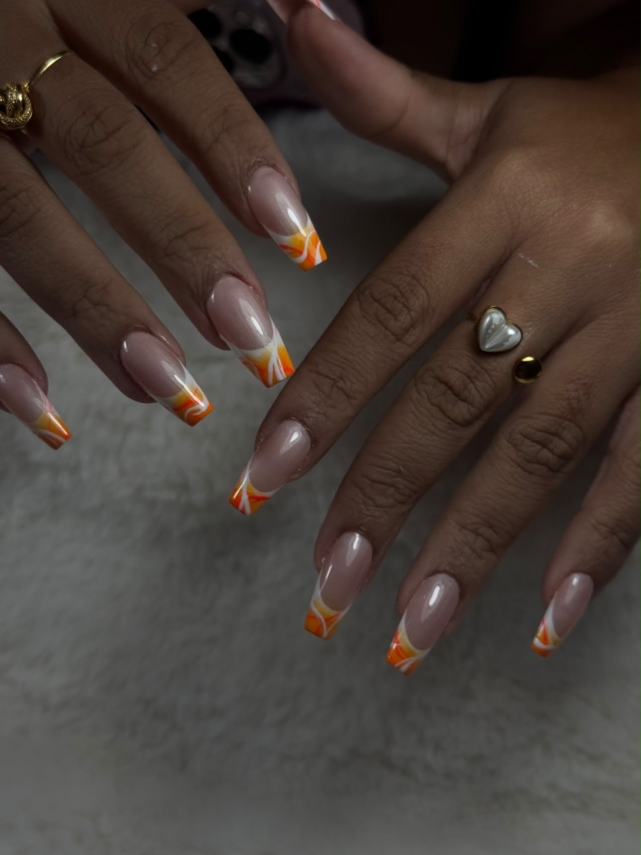 Ongles carrés à french torsadée orange, jaune et blanche sur base nude, ambiance feutrée